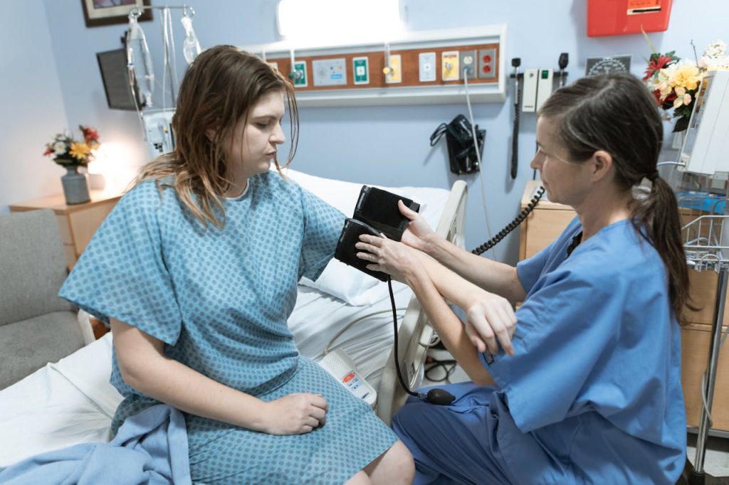 A nurse measures a patients blood pressure in a hospital room, focusing on healthcare and medical care.